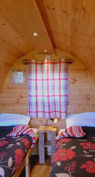 Two floral dressed beds inside Glamping Pod with the curtains closed